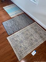 Shows all three rugs on wooden floor with sunlight, demonstrating size and coordinating colors