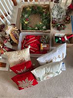 Overview of assortment of Christmas décor including wreath, pillows, figurines, candles.