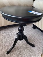 Side view showing the round top, pedestal column, and three-legged base