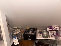 Wide view of pantry shelf showing party supplies including boxes of cups, spoons, and napkins.