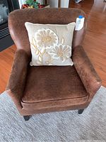 Front view of brown faux leather chair with floral pillow