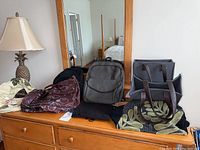 Overall view of five different bags on wooden dresser with lamp and mirror