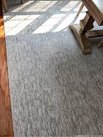 Close-up view of neutral tan and cream rug texture and color under sunlight.
