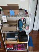 View of multiple items on shelving unit including boxes with buttons, hand sanitizer, fitness weights, and files.