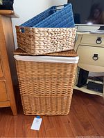 Photo showing stacked wicker laundry hamper with white cloth liner, sea grass basket on top, and other baskets.
