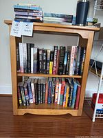 Front view of the book shelf filled with books, showing natural wood finish with slight wear and the overall size relative to the floor and surrounding items.