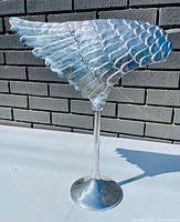 Photo of Nima Oberoi left wing cast aluminum metal sculpture mounted on metal stand against brick wall.