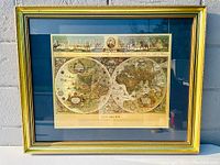 Framed Blaeu wall map showing two hemispheres and decorative cartouches with a gold frame and blue mat.