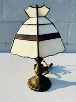 Front view of Tiffany style stained glass lamp showing white and red stained glass panels with black leading and scalloped top edge.