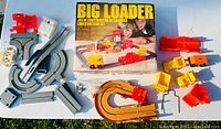 Overview image showing multiple plastic construction vehicles, track pieces, red and white structural elements, and the original box with title and children pictured.