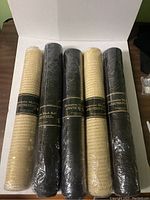 Five rolled mesh fabrics: three black and two beige, each wrapped in plastic and labeled Decorative Mesh Roll.