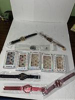 Overview photo showing 6 wristwatches with different colored straps and 5 boxes of costume rings in packaging.