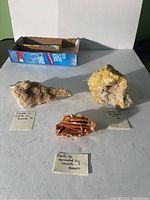 Lot overview photo showing all three rock crystal specimens on a flat surface next to a cardboard box.