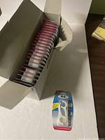 Open box showing multiple packs of Tek floss picks inside, stacked vertically.
