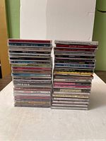 Two stacks of music DVDs and CDs arranged on a table, showing variety of genres and artists.