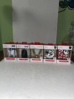 All 5 Hallmark ornament boxes displayed in a row showing the front of each boxed figurine.