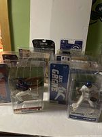 Multiple McFarlane sports figures displayed in original packaging, showing various sports like baseball, basketball, and hockey with clear logos and team uniforms.