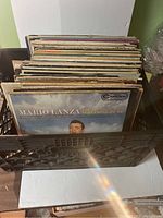 Black crate filled with multiple vinyl records, showing top spines and some front album covers, with Mario Lanza's album visible in front.