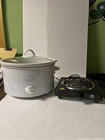Photo showing a white Rival Crock-Pot with glass lid and a black Bene Casa single coil electric burner.