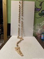 Front view of the full 65 inch alabaster wall rosary showing the beads and crucifix at the bottom.