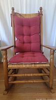 Front view of Kennedy rocker chair with red tufted reversible cushions on wicker seat and back.