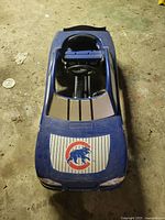 Top view of blue child's pedal car showing Chicago Cubs logo on hood with pinstripe design, visible wear and dirt.