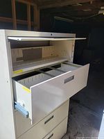 View of filing cabinet with drawer swung open, showing interior rails for hanging files