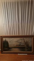 Framed original landscape painting depicting a rural farm river with pine and bare trees, cloudy sky. Signed by Polinus. Measures about 55x31 inches. Needs cleaning.