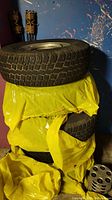 Four tires stacked in yellow plastic wrapping in garage corner