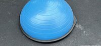 Top view of the blue inflatable dome of the Bosu Ball Balance Trainer on asphalt ground.