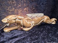 Side view of brown ceramic jaguar planter with light bulb cord in mouth