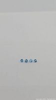 Four calibrated AAA quality Swiss blue topaz gemstones cut in trillion shape, each around 4x4mm, displayed on white background.