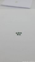 Five small rectangular-cut light green sapphires arranged on white background, clear image to show size and clarity.