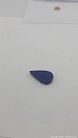 Photo of the pear-shaped deep blue lapis lazuli gemstone showing thickness and polished surface.