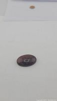 Oval cabochon natural mahogany jasper gemstone showing its rich reddish-brown color and natural markings.