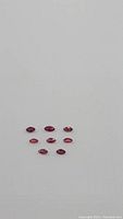 Eight marquis cut natural rubies arranged on a white background showing their color and clarity.