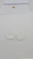 Two small translucent white natural selenite stones, one oval and one round, placed on white background with a coin for size reference.