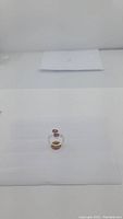 Photo of sterling silver garnet ring on a neutral white background showing front and side view with cherry red garnet stones.