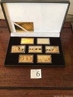 Full view of presentation box with six gold plated bank note bars in plastic holders and certificate inside.