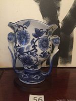 Front view of porcelain vase showing blue floral pattern and double handles with flower tips.