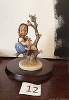 Front view of the Hummel Goebel figurine showing the girl sitting on a branch with blossoms and birds.