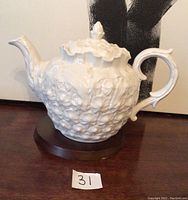 Side view of the white ceramic Spode teapot with pineapple texture, with lid on. Shows handle, spout, and overall shape.
