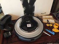 Shark robot vacuum cleaner with extra filters, blades, side brushes in packaging along with cleaning tools.