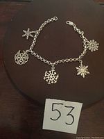 Full view of the sterling silver snowflakes bracelet displayed on a dark surface with a label number '53'.