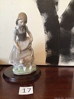 Front view of Lladro porcelain figurine of a girl with a cat on a wooden base.