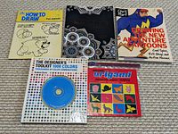 All five books laid out flat on a carpet, showing front covers including drawing, coloring, design, and origami books.
