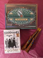 Box of Golden Snitch Quidditch board game sealed in shrinkwrap, Codenames Harry Potter board game box, two electronic Magic Spell Challenge wands with star decorations and Harry Potter branding