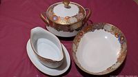 Four-piece Japanese Satsuma porcelain serving dish set on red surface showing all items.