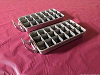 Two vintage aluminum ice cube trays side by side showing the tray and lever mechanism