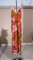 Full front view of a colorful maxi sundress hanging on a rack showing the overall length and pattern.